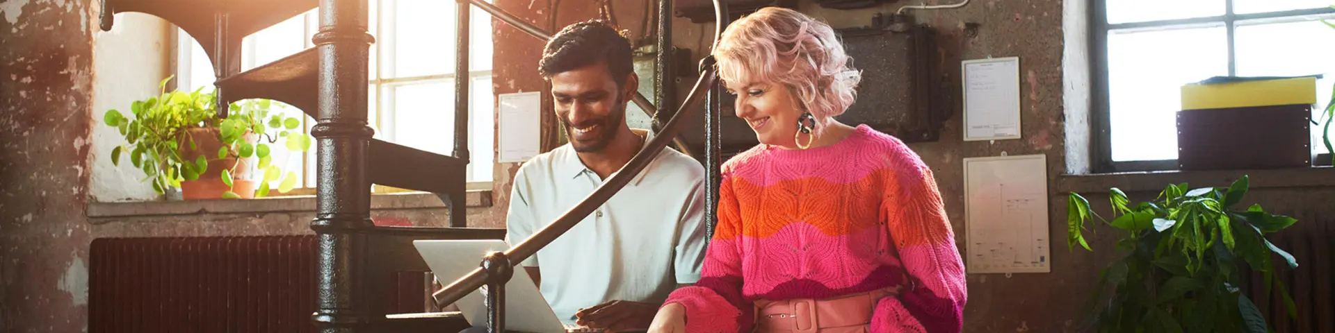 Mörk man och kvinna med röd tröja tittar på dator