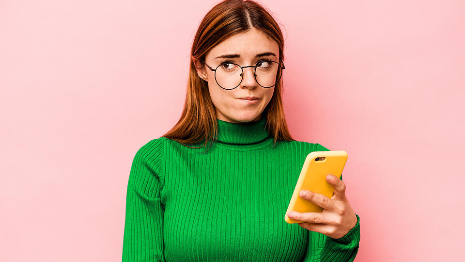 Kvinna mot rosa bakgrund, med grön mobil i handen