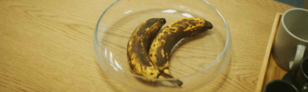 Två gamla och bruna bananer som ligger i en glasskål