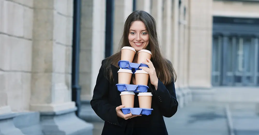 Kvinna som balanserar många take away-kaffe.