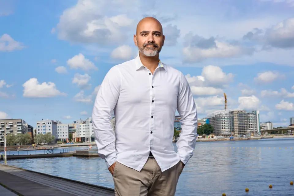 Kristian Saliba, pluggar. Vit skjorta. Stad i bakgrunden. 