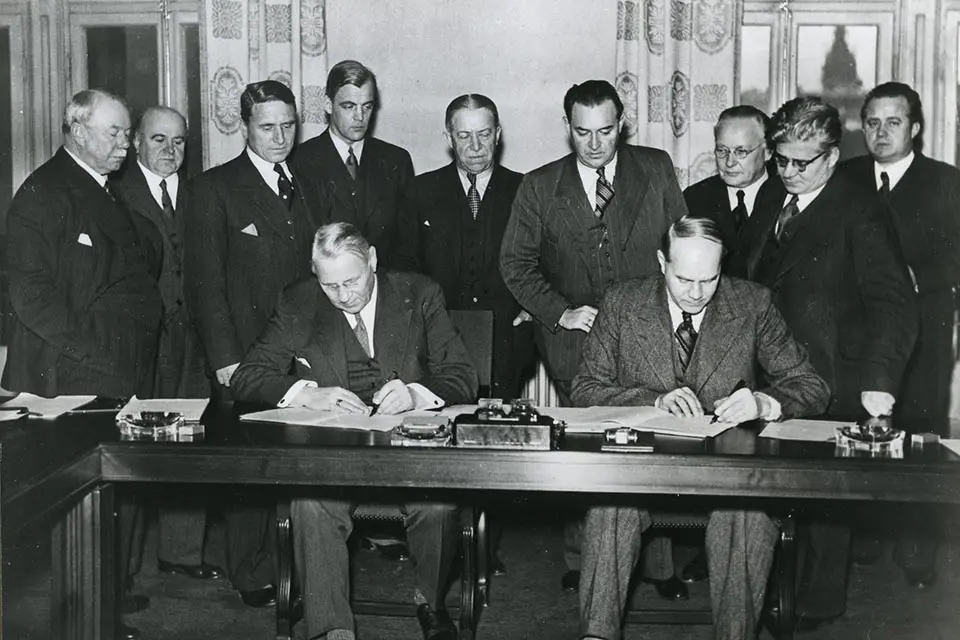 Foto på August Lindberg, ordförande i  LO, och Gustav Söderholm, VD för SAF, skriver under Saltsjöbadsavtalet 1938. 