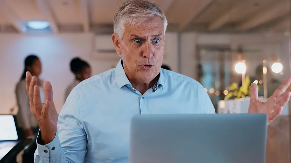 Man i blå skjorta, irriterad framför dator 