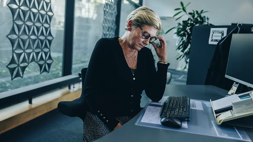 Kvinna vid dator, i svart tröja, som ser uppenbart oroad ut. 