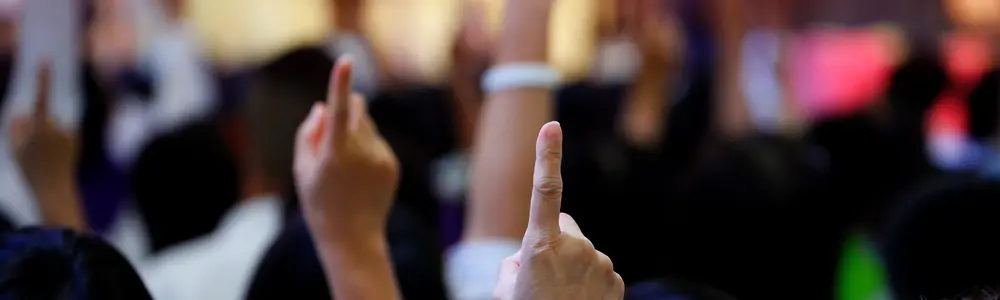 Händer som sträcks upp för rösta i en publik