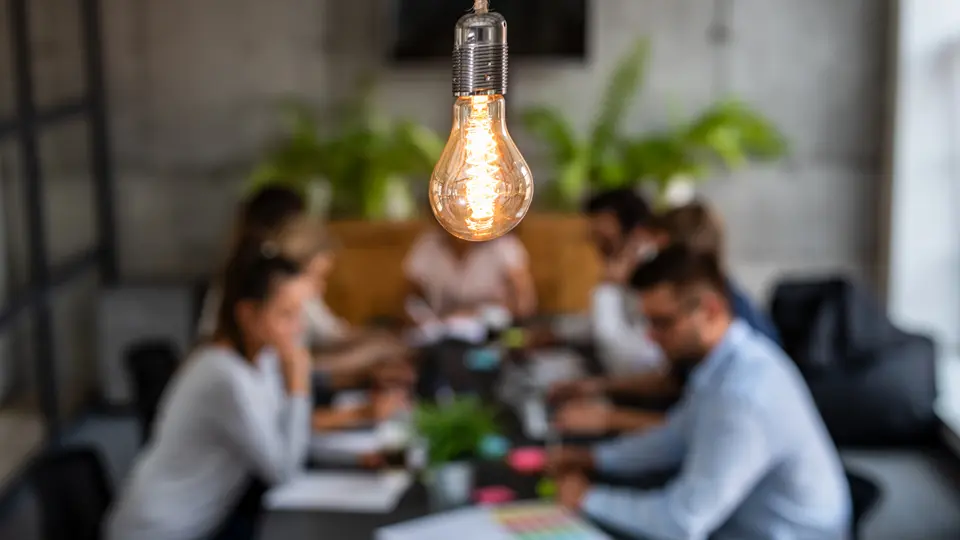 Personer runt bord och glödlampa