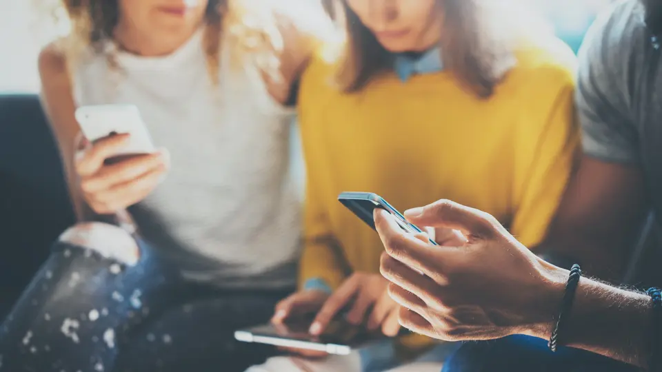Tre personer som sitter med mobiler i handen
