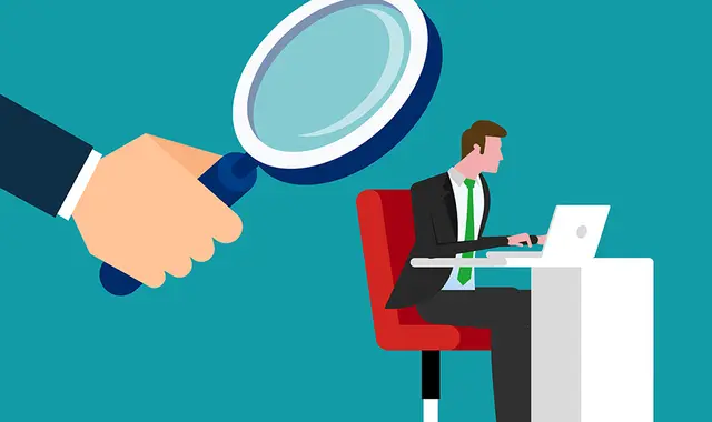 Chef som kollar på tjänsteman i förstoringsglas. 