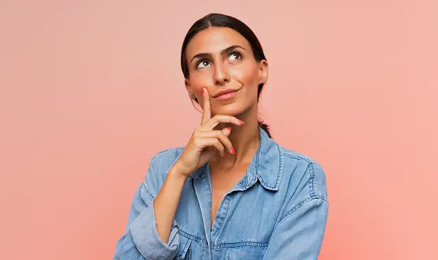 Kvinna i jeansskjorta som står och funderar. 