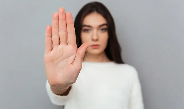 Tjej som håller upp handen och säger stopp. 