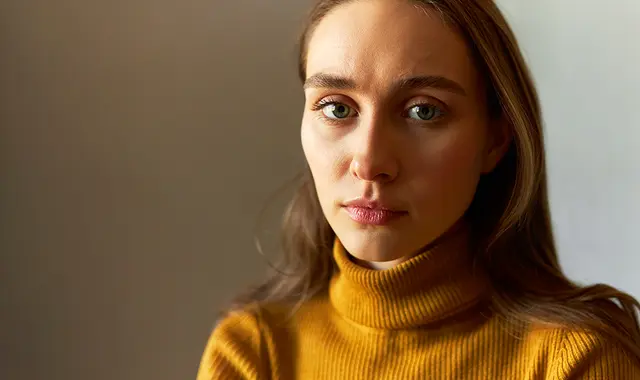 Utmattad kvinna i gul tröja.