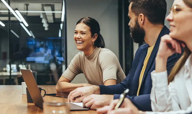 Två kvinnor och en man vid ett konferensbord. Alla tre ser glad ut. 