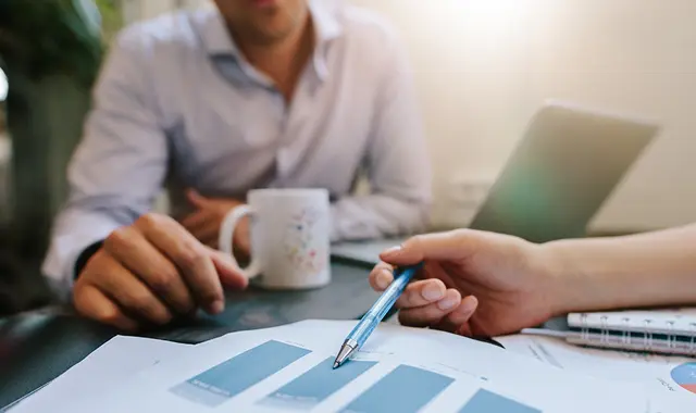 Kvinna och man förhandlar över ett bord. Man ser mest bara deras händer. 