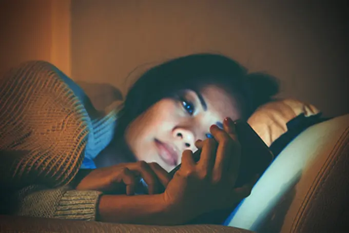 person i säng med mobil