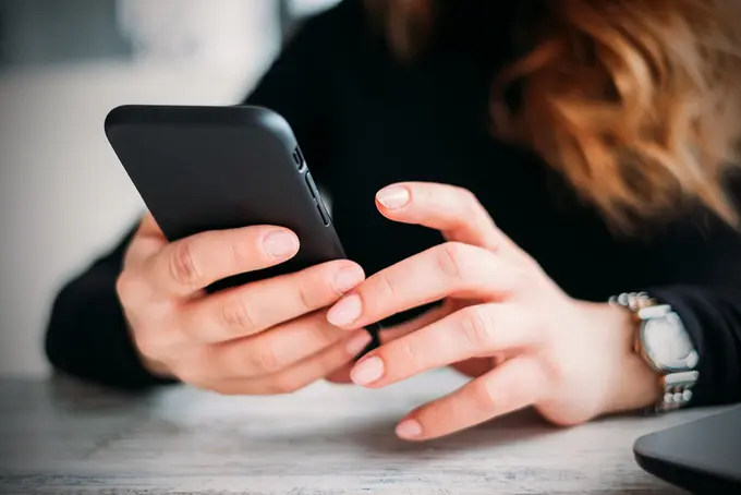 händer som håller i mobiltelefon