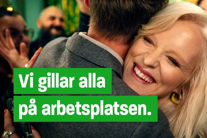 Två personer, en kvinna och en man, kramas på en fest och viser att hon är jätteglad.