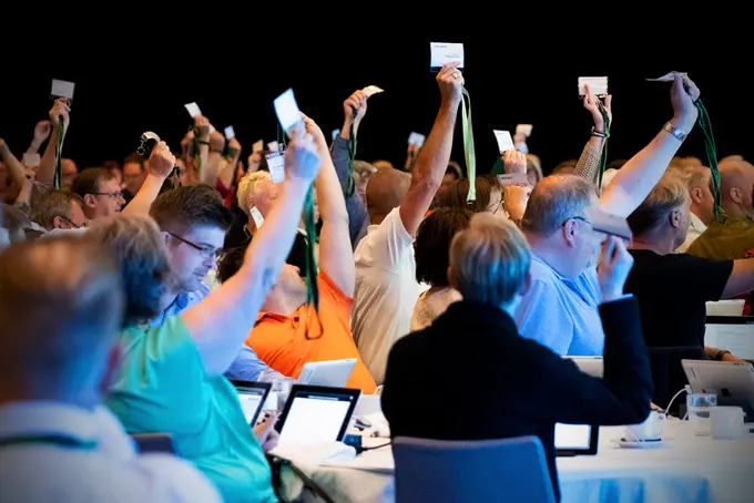 Foto på personer med röstkort i mötessal