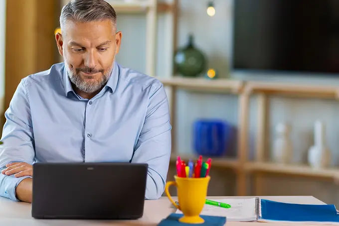 En leende person skriver på sin laptop