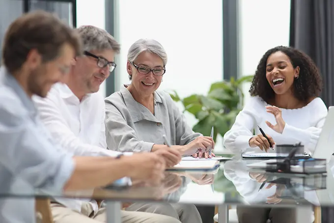 Fyra tjänstemän i olika åldrar vid jobbskrivbord
