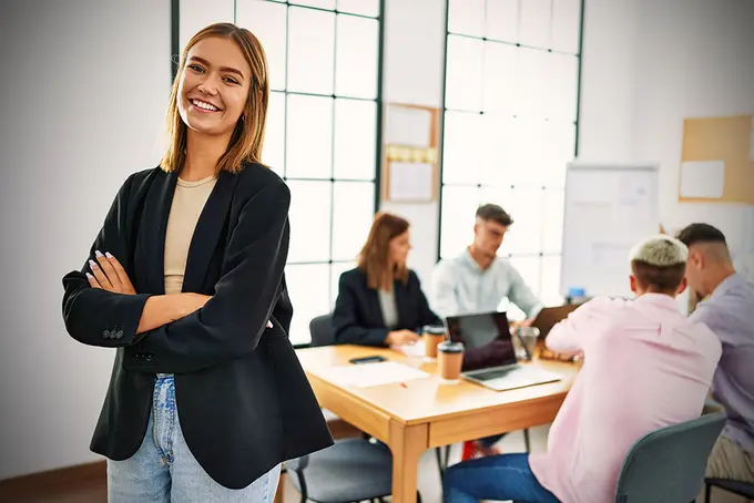 Ung kvinna som står framför en aktiv arbetsgrupp på kontor