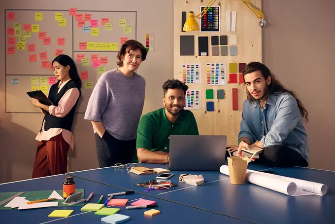 Tre män och en kvinna vid pingisbord med postit-lappar