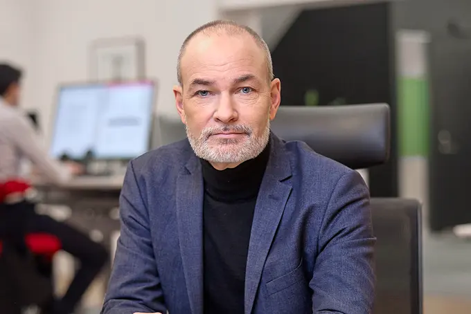 Man i kavaj ser in i kameran