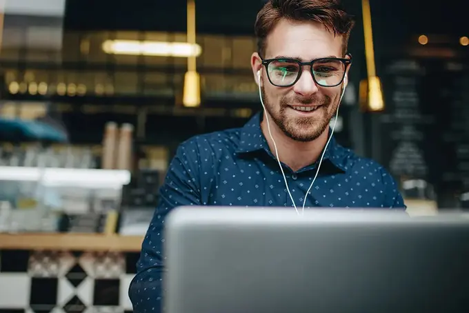 Glad man som sitter bakom dator