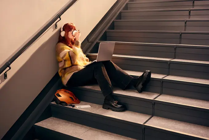 Kvinna som sitter i trappa med hörlurar