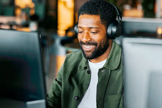 Man med hörlurar som sitter vid datorskärm