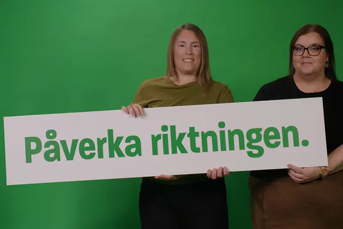 Två personer håller en lång skylt med texten "påverka riktningen".