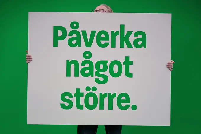 Person med gigantisk skylt med texten "Påverka något större". 