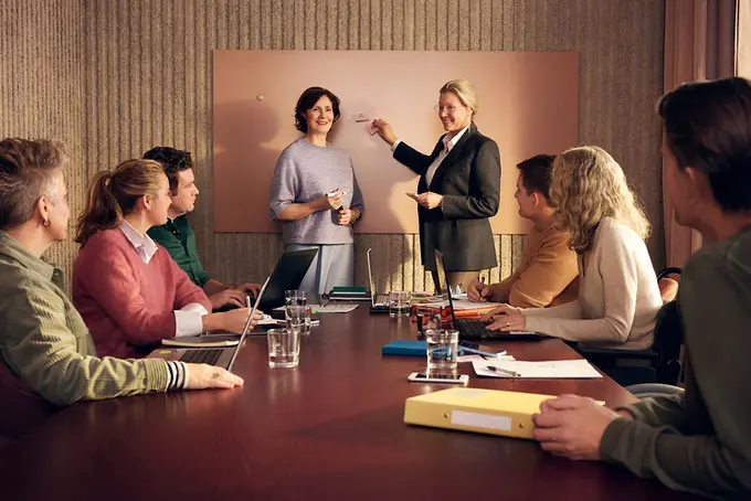 Gruppmöte med två kvinnor vid whiteboard