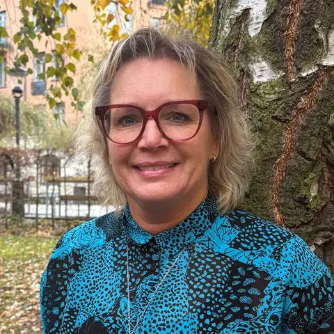 Porträttfoto på en leende Johanna Strandlund framför en höstig björk